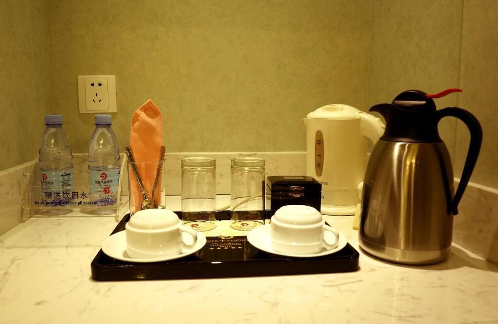 A breakfast tray with two cups, a thermos, and bottled water on a marble countertop.