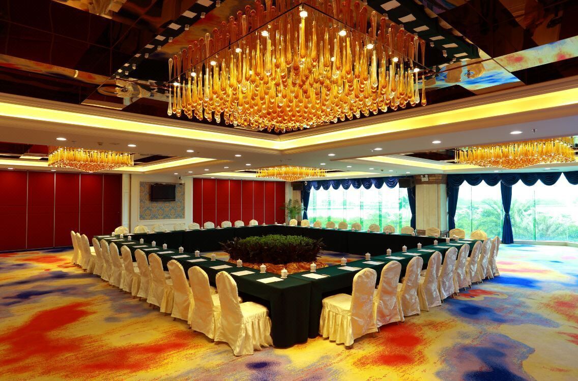 A conference room with a long table, white chairs, and a chandelier.