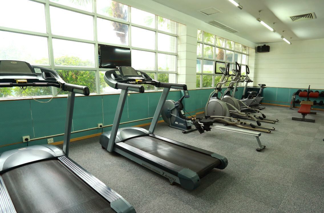 Un gimnasio con cintas de correr, bicicletas estáticas y máquinas de pesas.