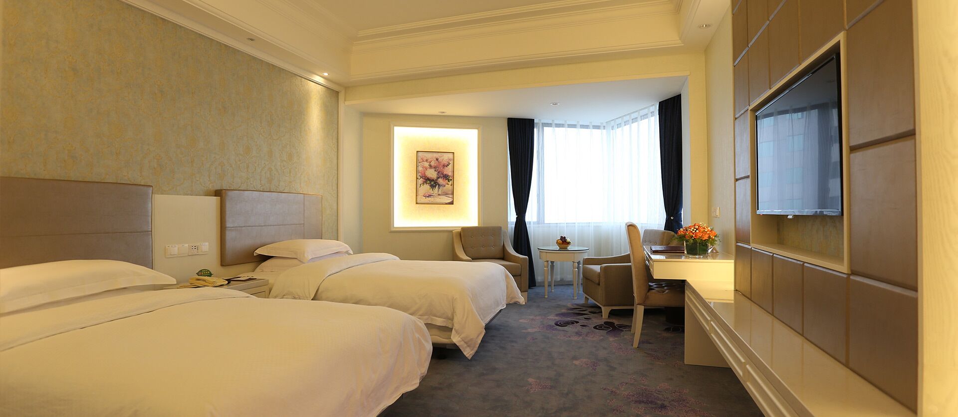 Habitación de hotel con dos camas, un escritorio, una silla, un televisor y una ventana con cortinas.