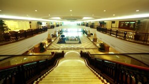 A spacious lobby with a central seating area, multiple levels connected by a staircase, and a large glass railing. - Pantower International Hotel (Jiangmen)