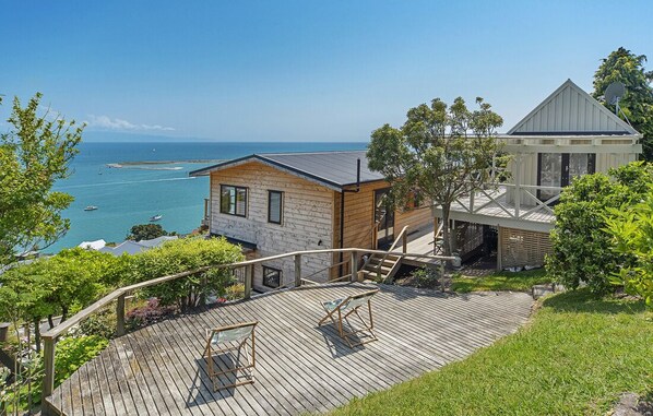Une propriété située sur la côte, dotée d’une terrasse en bois, d’un petit chalet et d’un bâtiment plus grand avec un toit en pente.