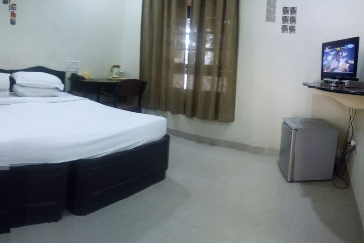 Habitación de hotel con una cama grande, un escritorio, una silla, un televisor y un refrigerador.