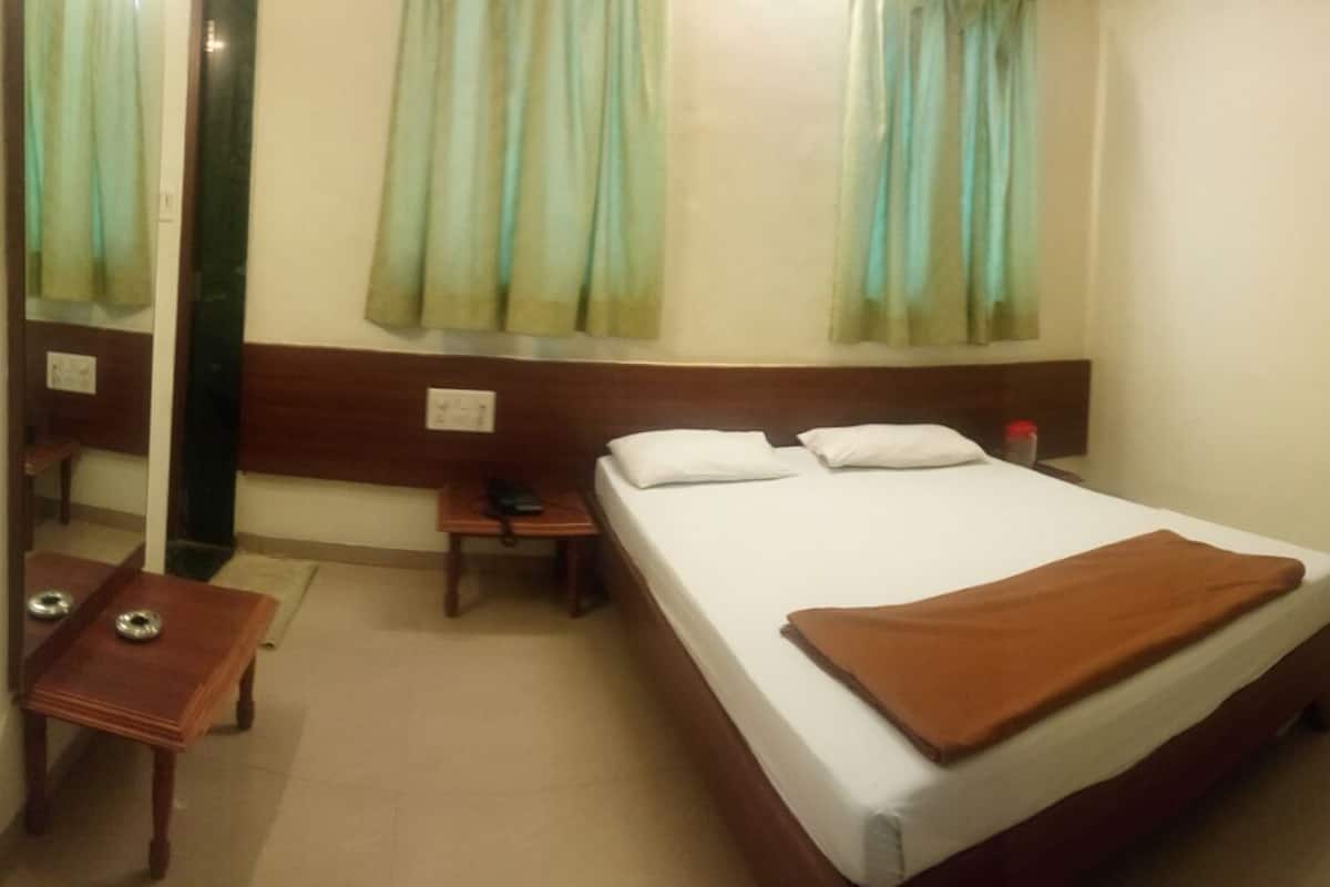 Una habitación de hotel con una cama individual, una mesita de noche, una silla y un escritorio.
