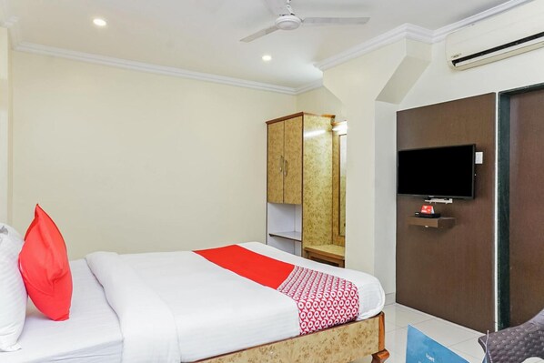 A hotel room with a bed, a television, a wardrobe, and a ceiling fan. - Hotel Rajdeep (Pune)