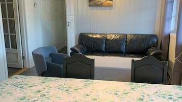 Um quarto com cama, sofá, mesa de jantar com cadeiras e um quadro na parede.