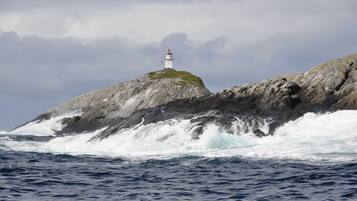 A lighthouse on a rocky outcrop with waves crashing against it.