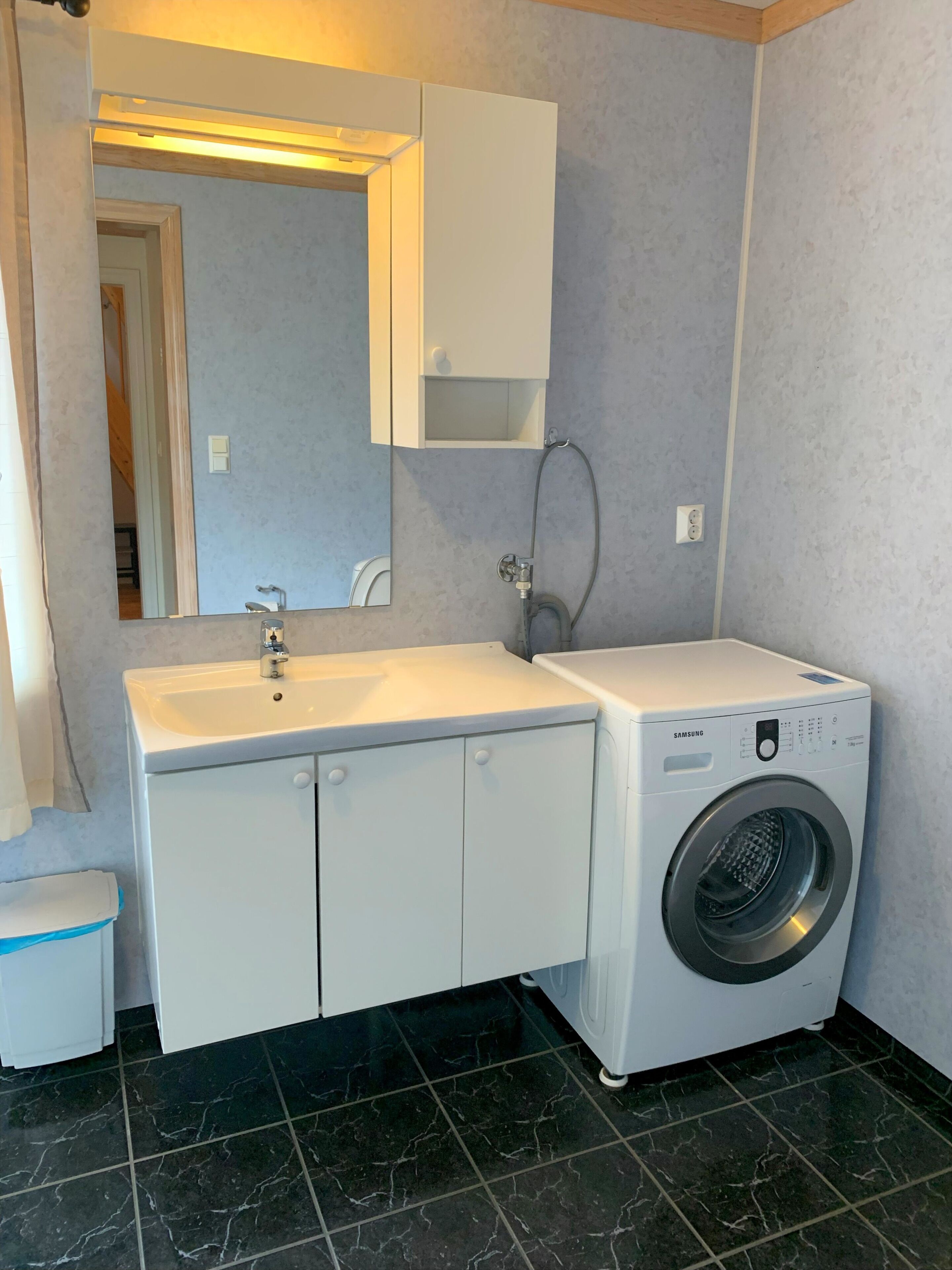 Un baño pequeño con un lavabo blanco, un espejo, lavadora y un inodoro.