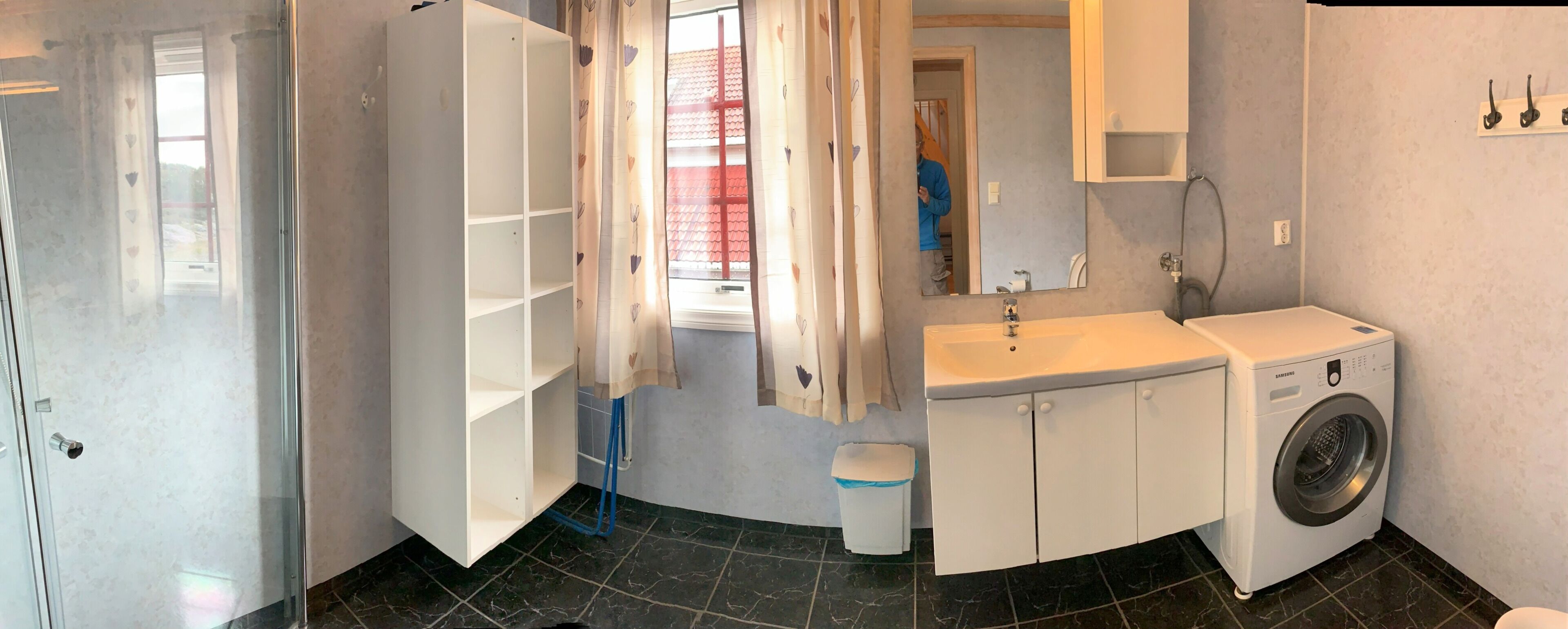 A bathroom with a white sink, a washing machine, a mirror, and a toilet.