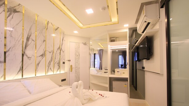 A hotel room with a large bed, a mirror, a TV, and a minibar. - Pratunam Atrium Hotel (Bangkok)