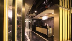 A modern hotel lobby with a reception desk, marble flooring, and a chandelier. - Pratunam Atrium Hotel (Bangkok)