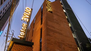En høj murstensbygning med et neonskilt, der viser ordene Hotel Olive.