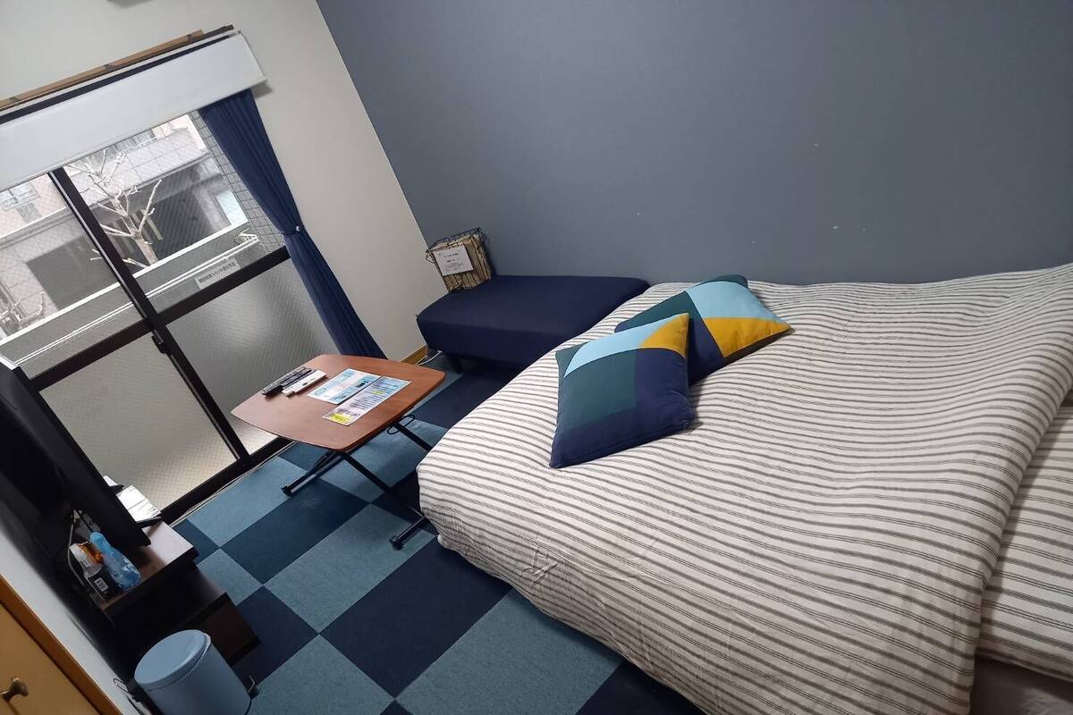 A compact hotel room with a bed, a small desk, and a window.