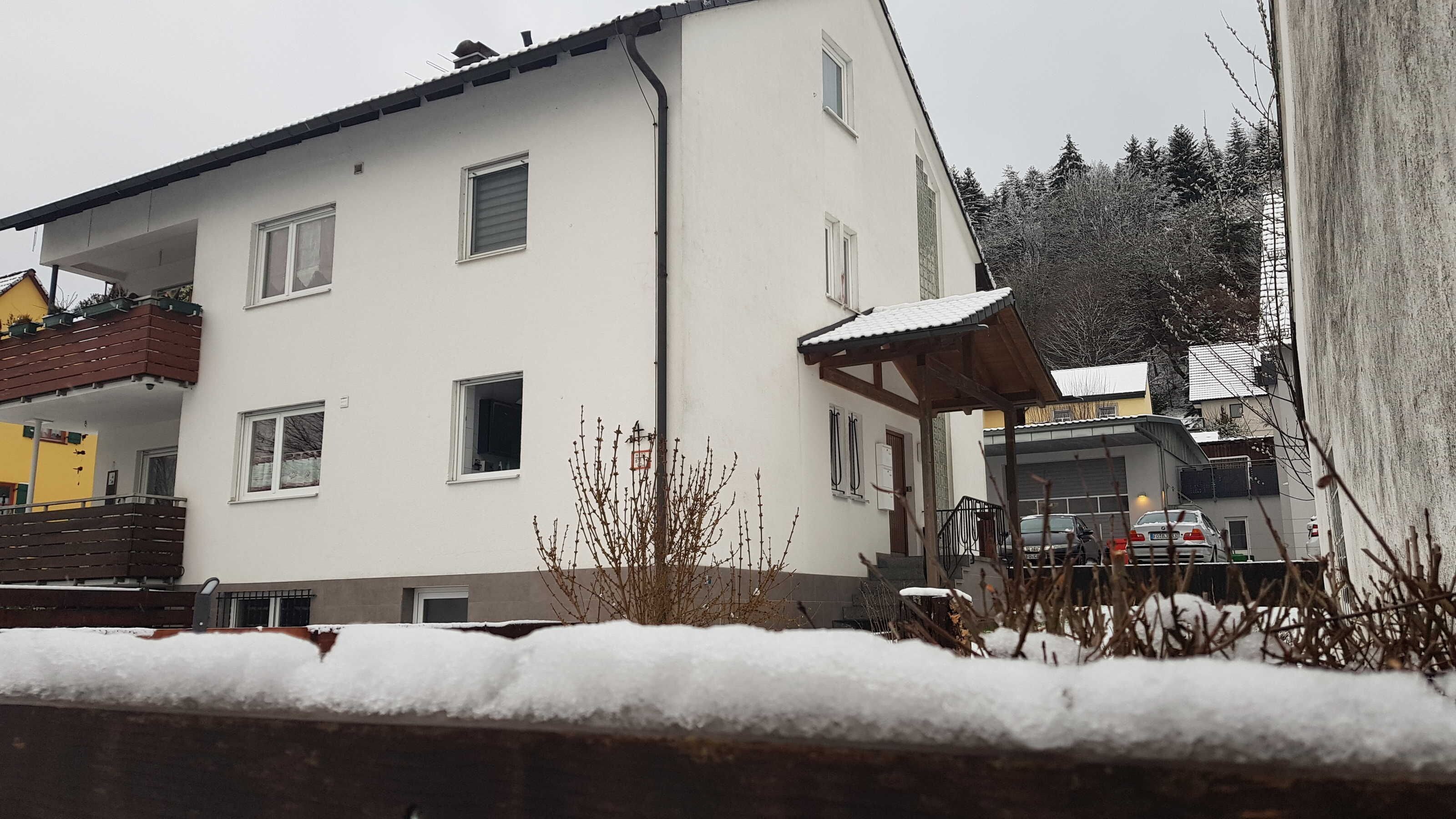 Ein zweigeschossiges Gebäude mit weißer Fassade, zahlreichen Fenstern und einem überdachten Außenbereich.