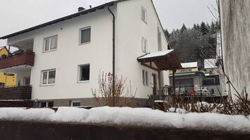 Ein zweigeschossiges Gebäude mit weißer Fassade, zahlreichen Fenstern und einem überdachten Außenbereich.