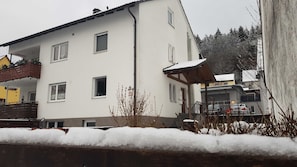 Un edificio a due piani con facciata bianca, numerose finestre e un'area esterna coperta.
