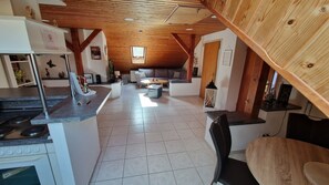 A spacious loft-style living area with a high ceiling, a kitchen with modern appliances, and a cozy seating area with a sofa and coffee table.