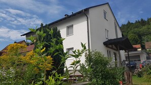 A two-story building with a white exterior, a visible garage, and a covered porch. - Vacation apartment Schwarz (Ebermannstadt)