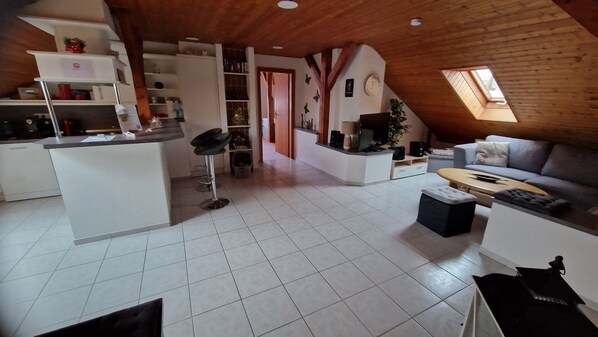 A spacious living area with a kitchen, a dining table, and a sofa.