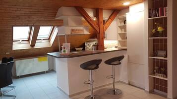 Eine Küche mit Holzbalkendecke, einer Arbeitsplatte mit Barhocker und einem Fenster.