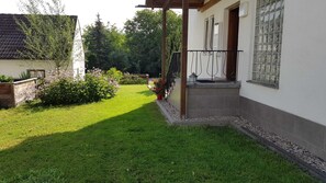 Un giardino curato con prato, un pontile in legno e un edificio con rivestimento in tegole.