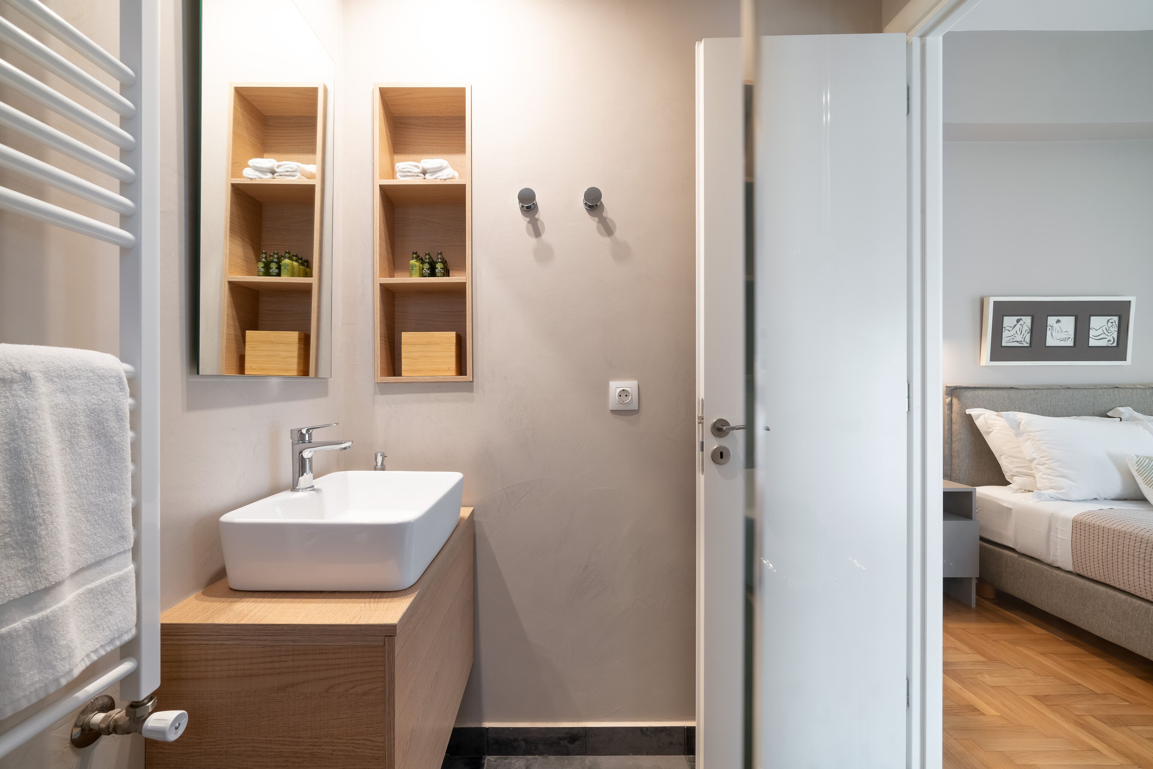 A modern bathroom with a white sink, wooden cabinets, and a shower area.