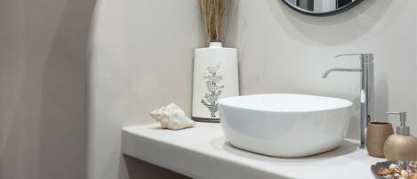A bathroom with a white vanity, a round mirror, and a white sink.