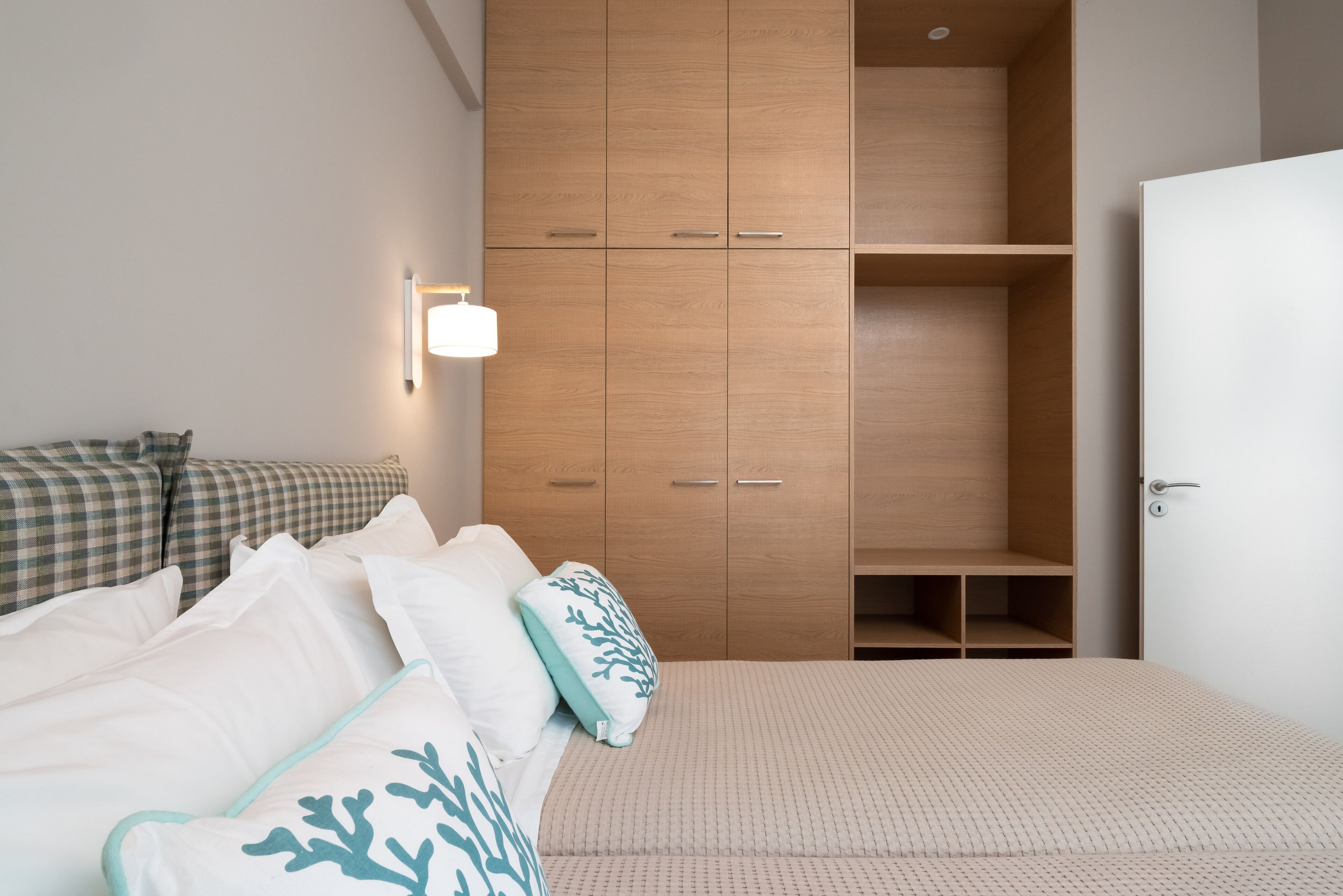 A bedroom with a bed, a wardrobe, and a bedside lamp.