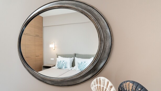 A round mirror with a beaded frame on a wall. - Absolute Athens Apartments (Athens)