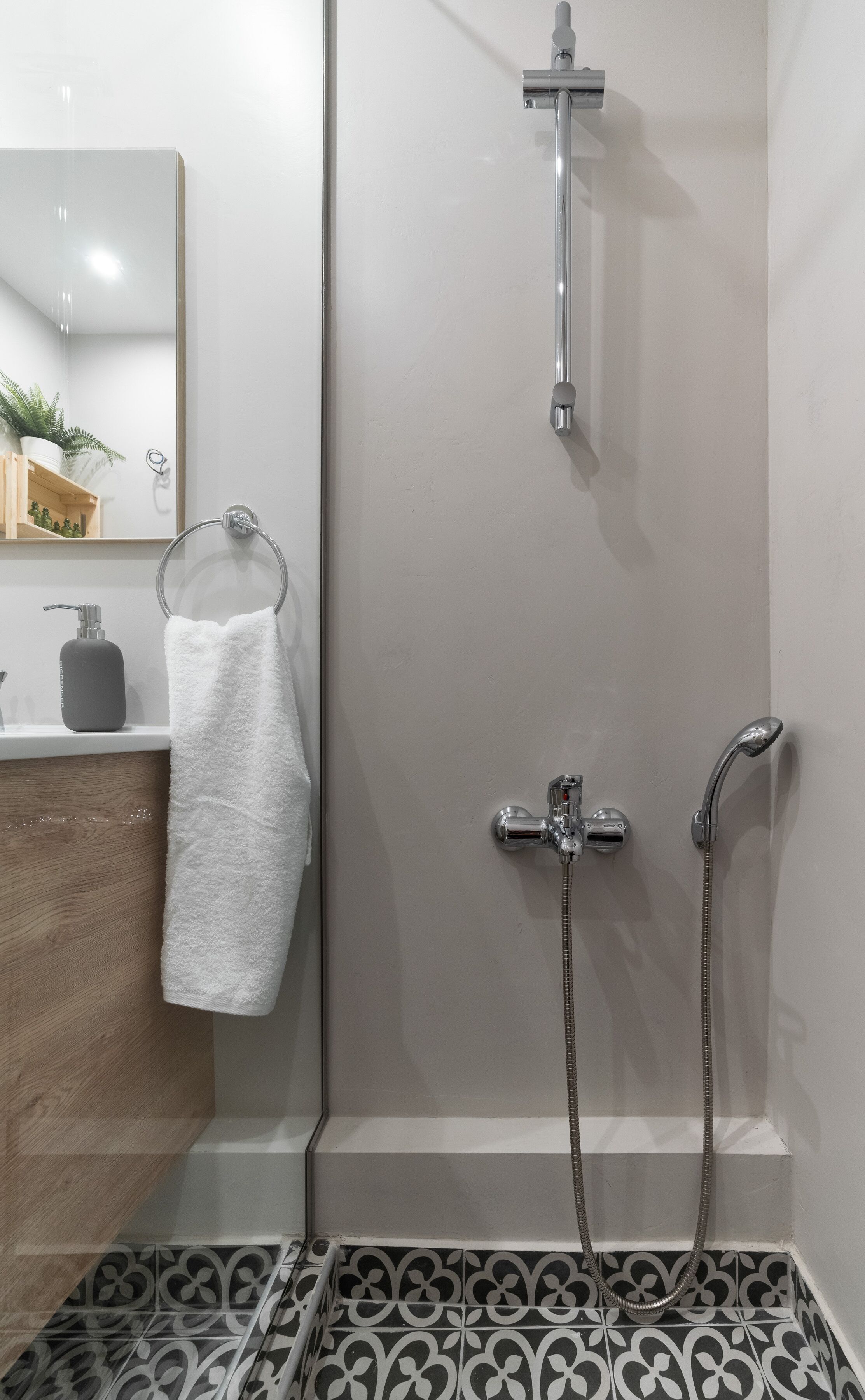 A bathroom with a shower, a sink with a mirror, and a towel hanging on the wall.