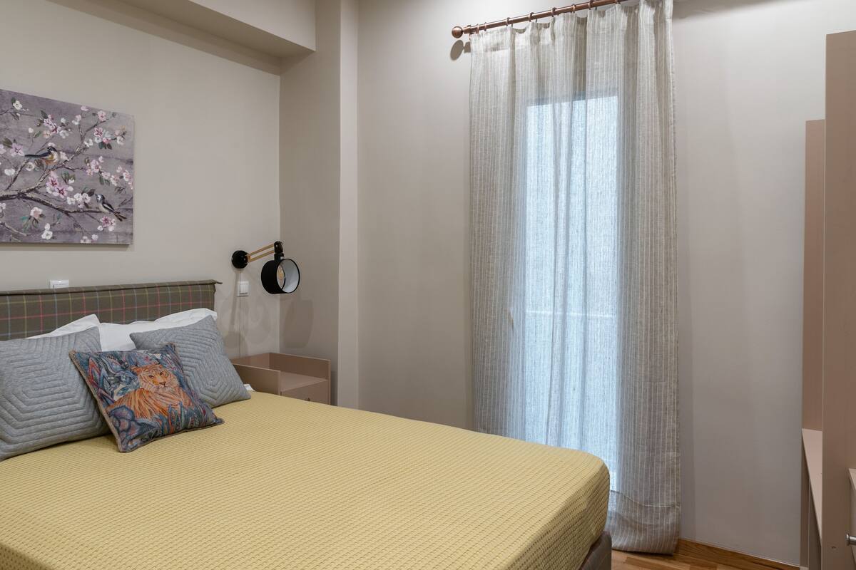Une chambre à coucher avec un lit, des oreillers, une lampe fixée au mur et un tableau.