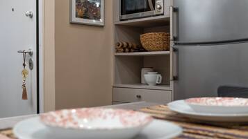 Una kitchenette equipada con microondas, refrigerador y estantes con utensilios de cocina.