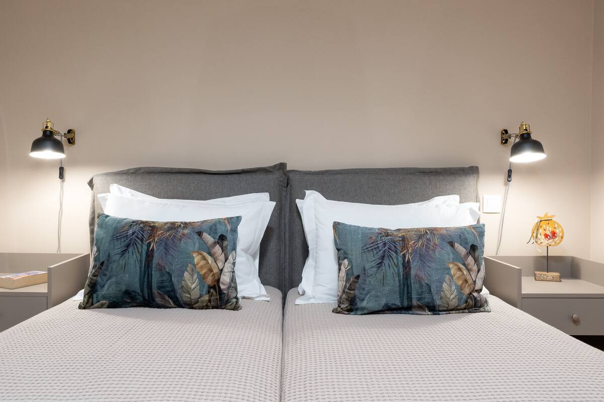Une chambre à coucher aux lignes symétriques, avec un grand lit, deux tables de chevet et deux lampes.