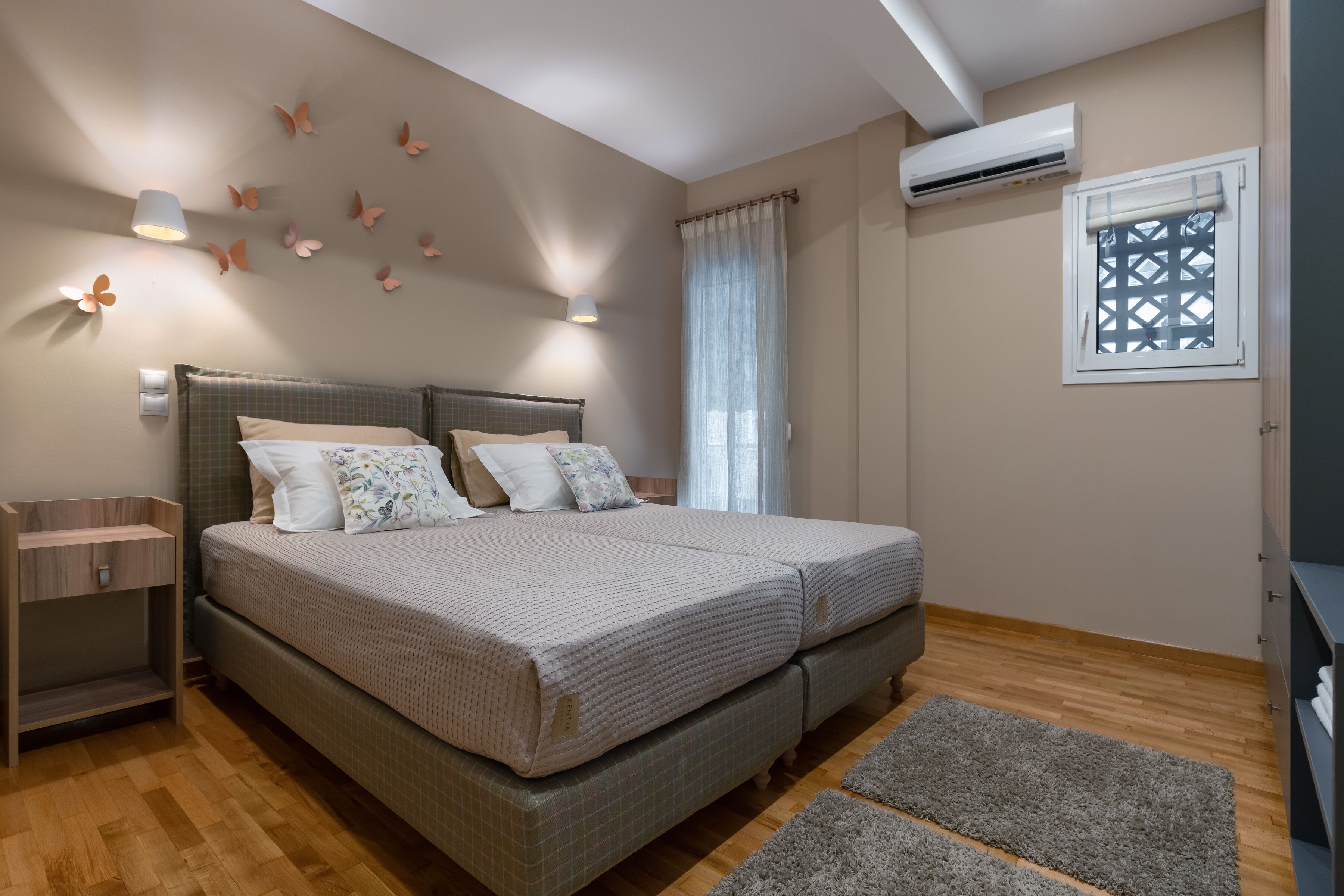 Un dormitorio con una cama doble, mesitas de noche, ventana con vistas y equipo de aire acondicionado.