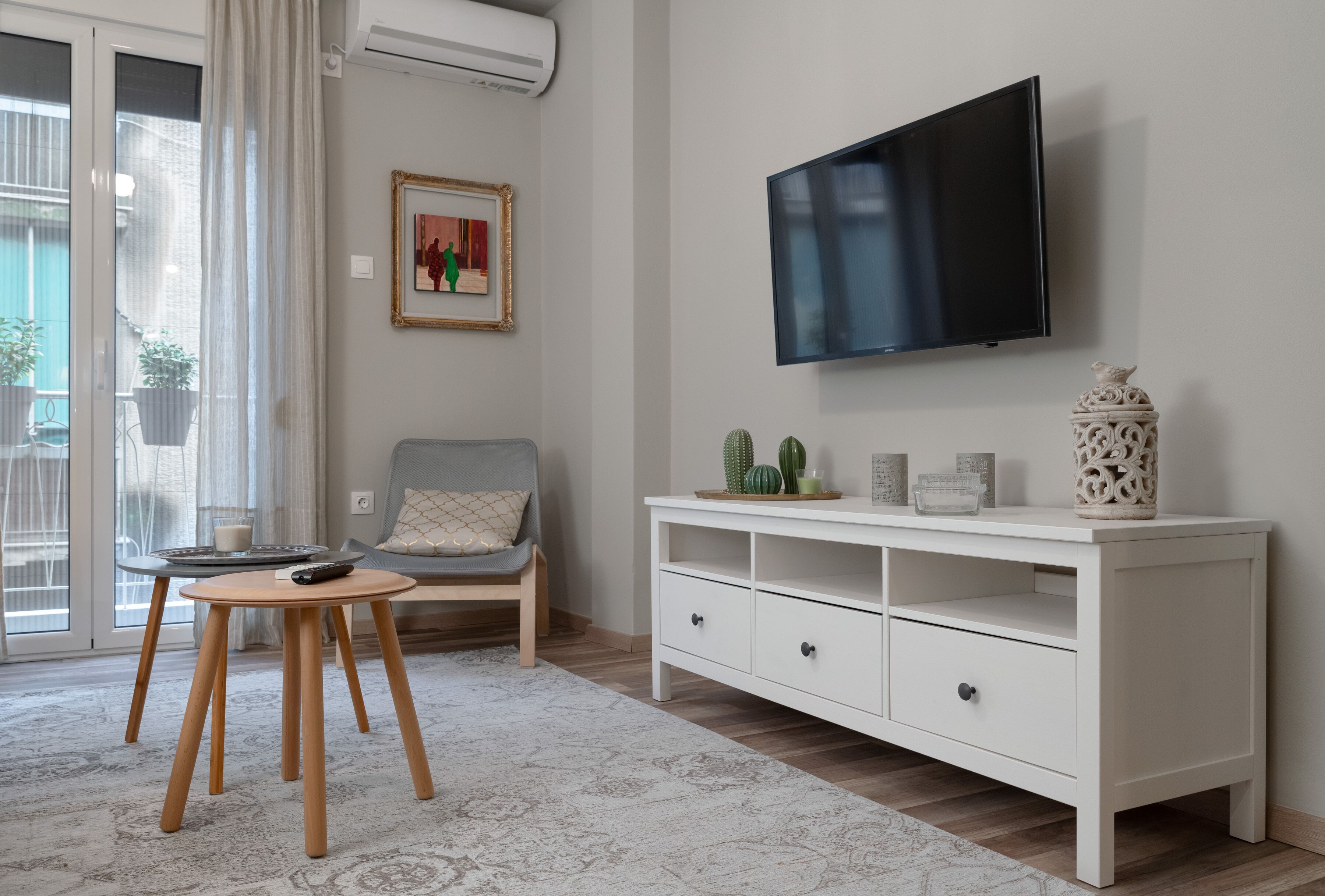 A living room with a TV, a white cabinet, a chair, and a small table.