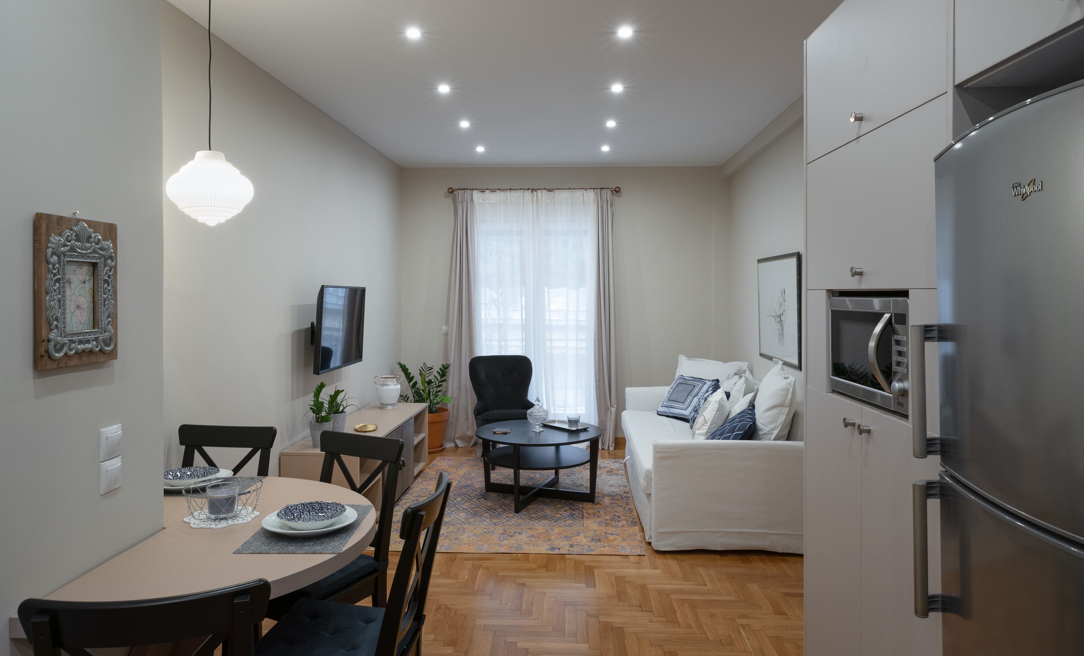 A compact living space with a dining area, a sofa, a TV, and a refrigerator.