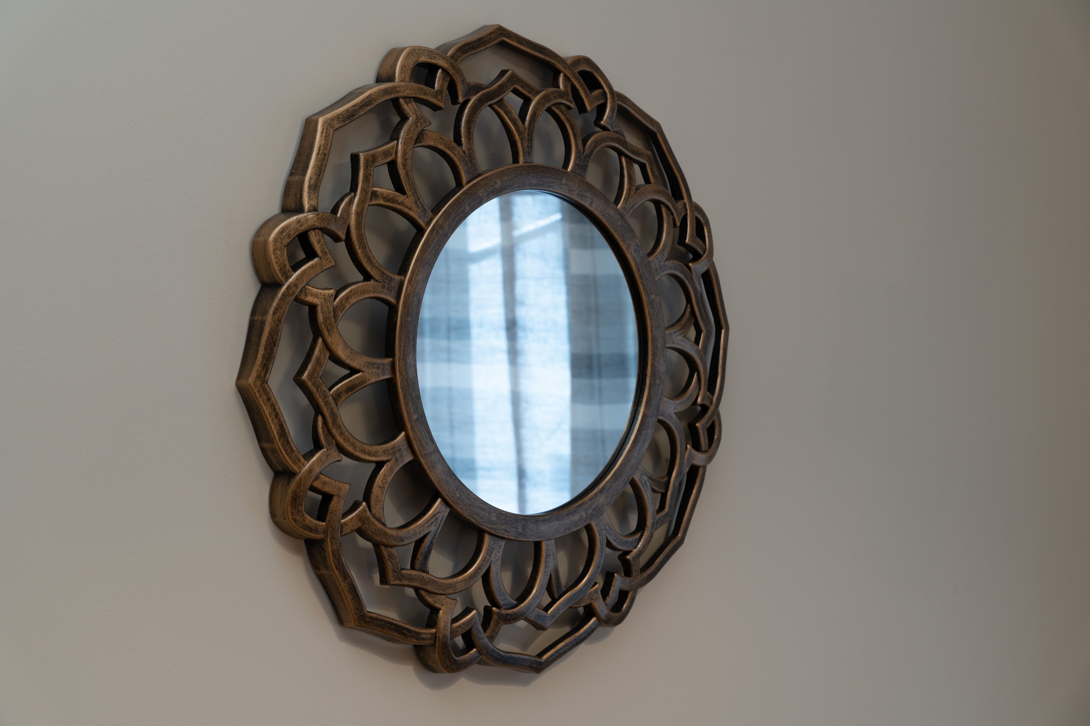 A wall-mounted mirror with an ornate, geometric frame.