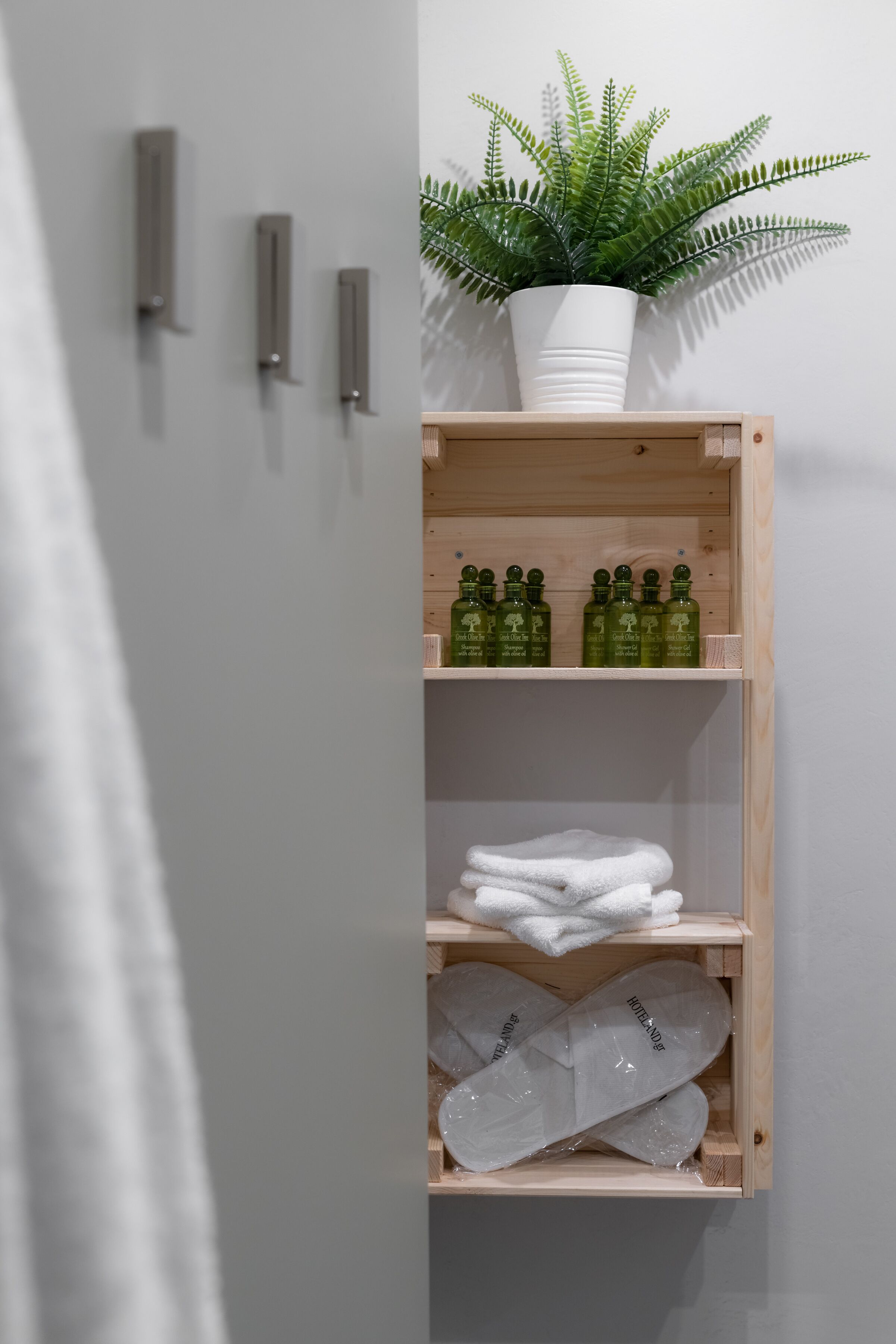 A bathroom with a wooden shelf holding toiletries, a potted plant, and a towel rack.
