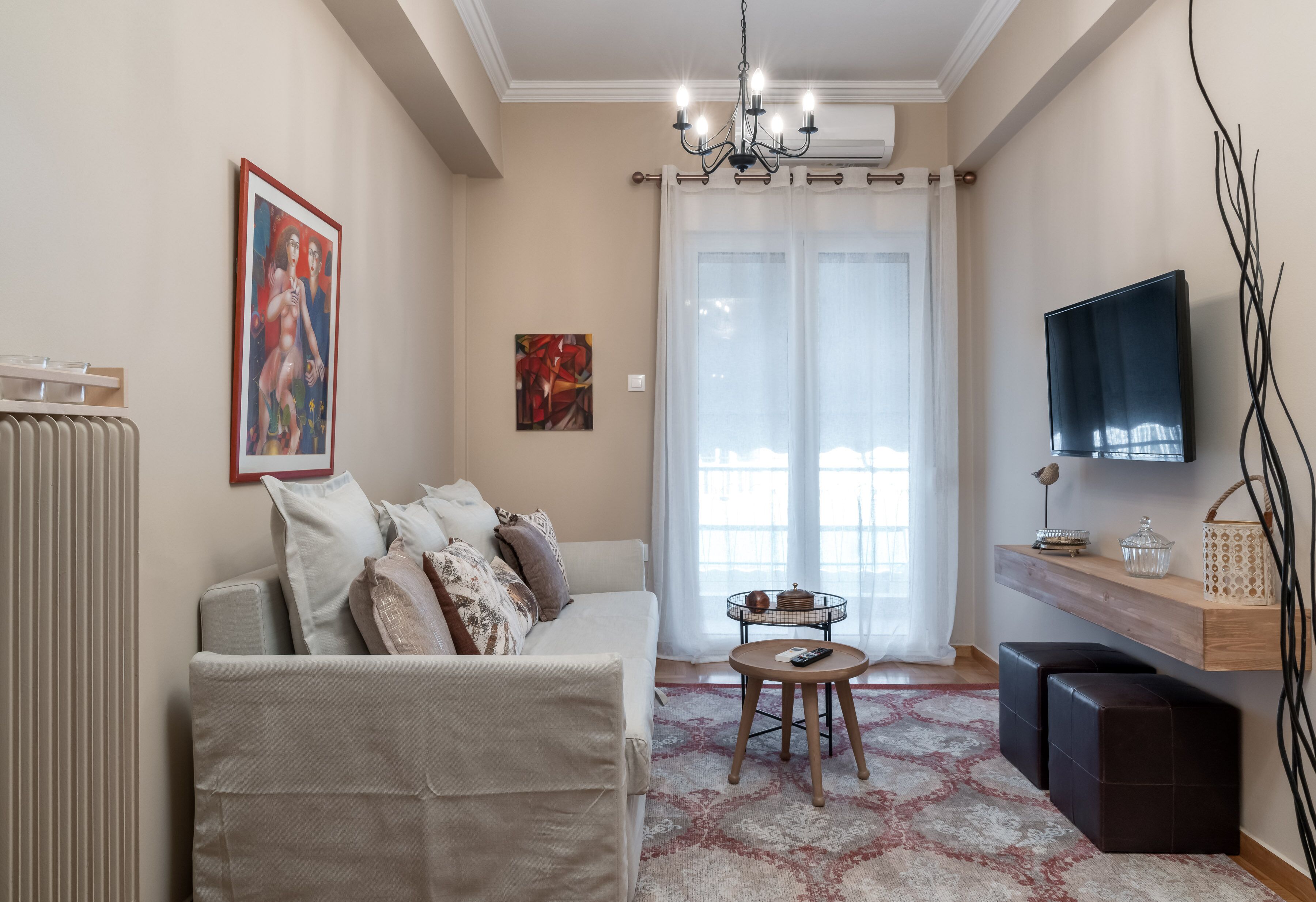 A living room with a sofa, a coffee table, a TV, and a radiator.