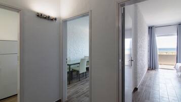 Habitació d'hotel amb sòl de fusta, zona de menjador amb taula i cadires, i balcó amb vista al mar.