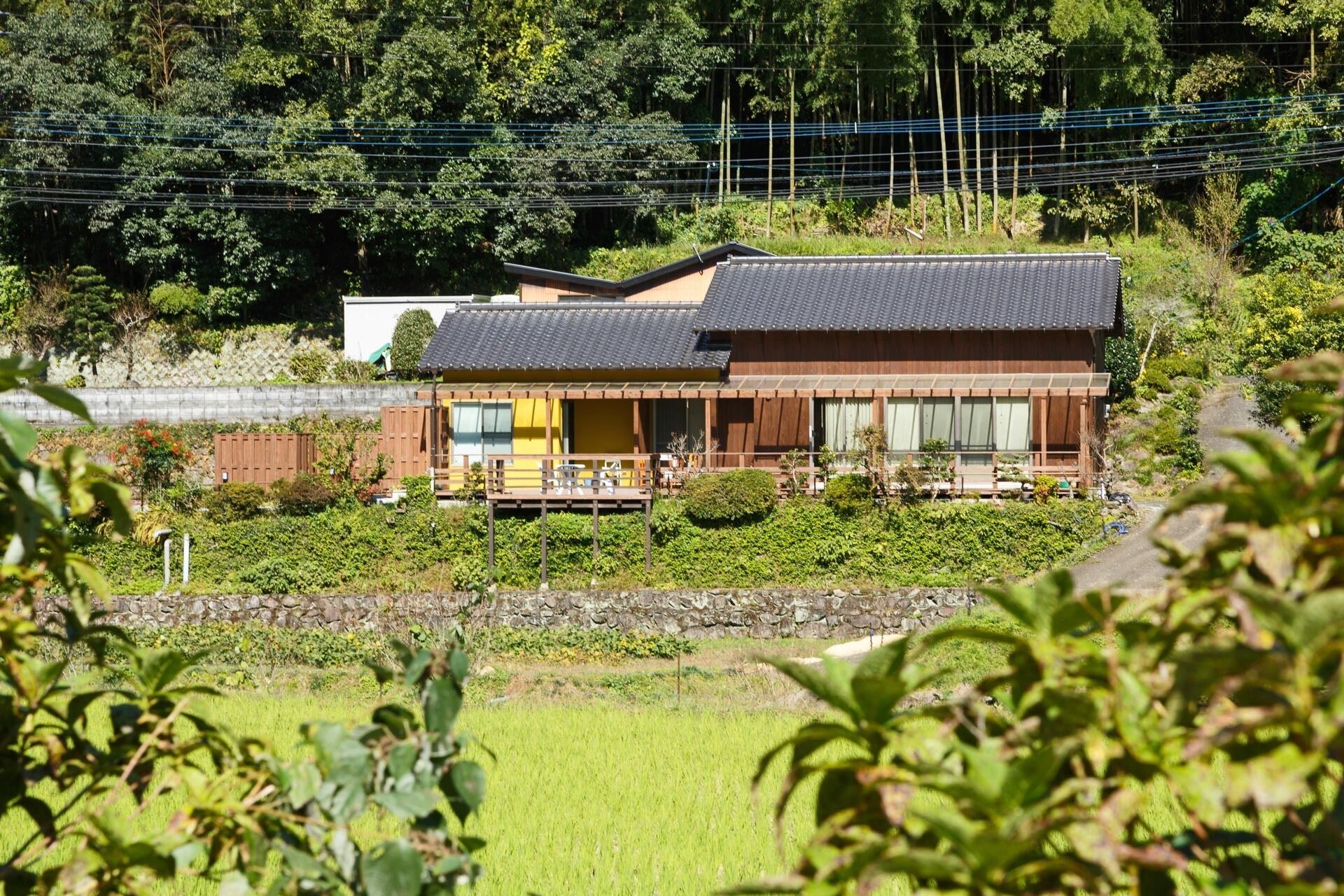 A traditional Japanese house with a wooden exterior, a tiled roof, and a small porch area.
