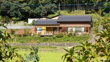 A traditional Japanese house with a wooden exterior, a tiled roof, and a small porch area.