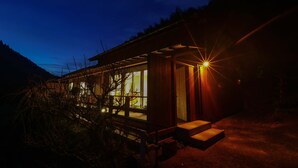 A modern building with large windows and a wooden exterior, surrounded by trees. - Ukiha Kojio no Akari (Ukiha)
