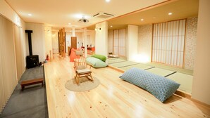 A traditional Japanese room with tatami flooring, a low wooden table, a cushioned chair, and a futon bed. - Ukiha Kojio no Akari (Ukiha)