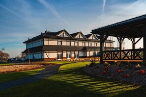 A large, two-story building with a traditional architectural style, featuring a prominent entrance and a covered outdoor area. - Sezony. Restauracja i Hotel (gmina Kostrzyn)