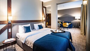 Une chambre d’hôtel avec un grand lit, une petite table sur laquelle se trouve un livre, un canapé et une lampe.
