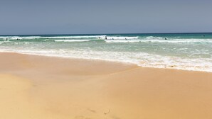 Una playa con cielos despejados y olas tranquilas.