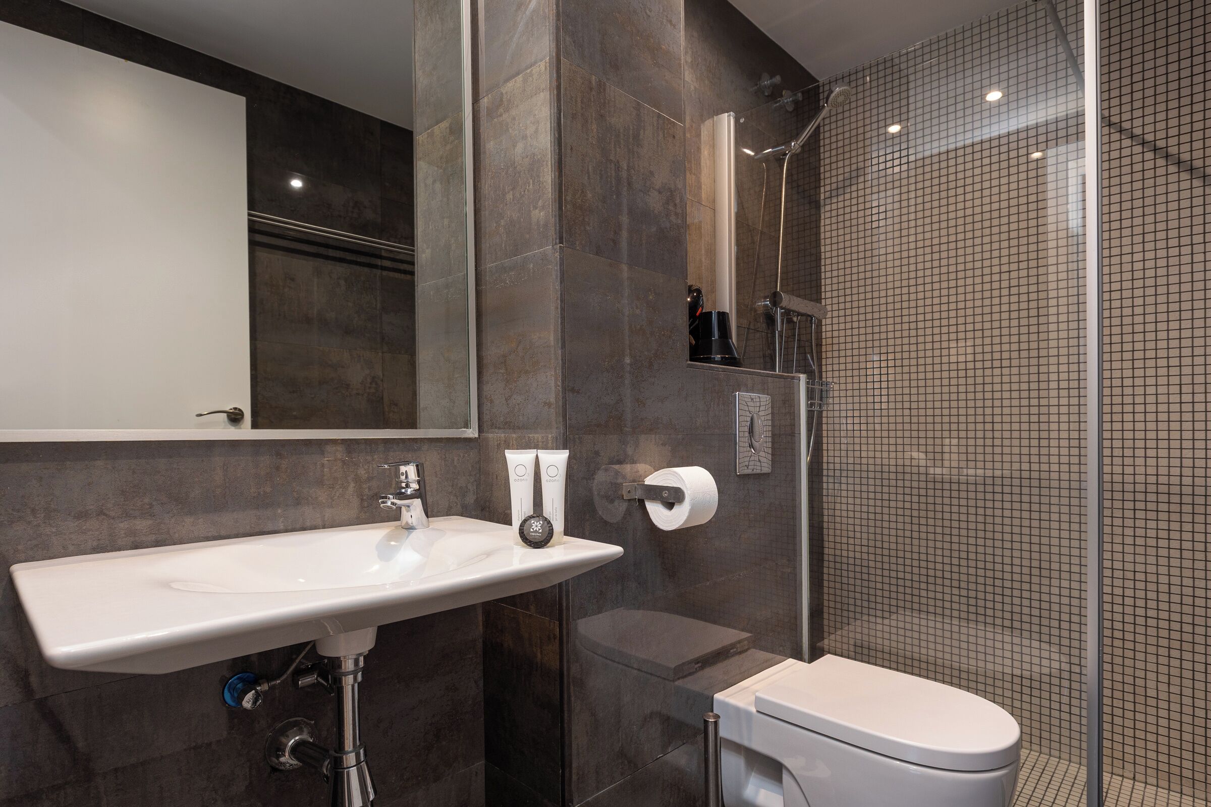 Een moderne badkamer met een wit wastafelmeubel, toilet en een douche met glazen wanden.