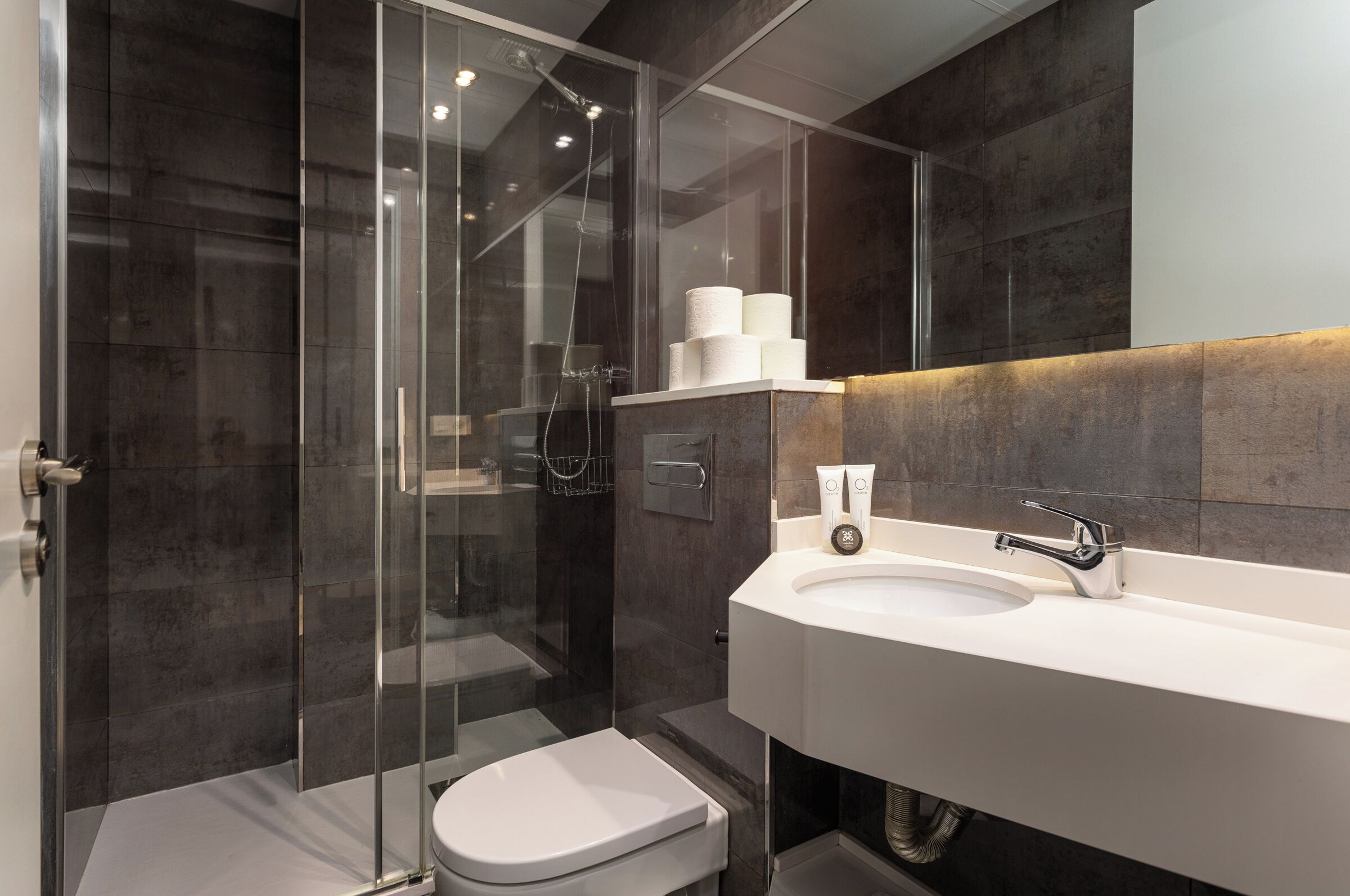 A modern bathroom with a glass-enclosed shower, a white sink, and a toilet.