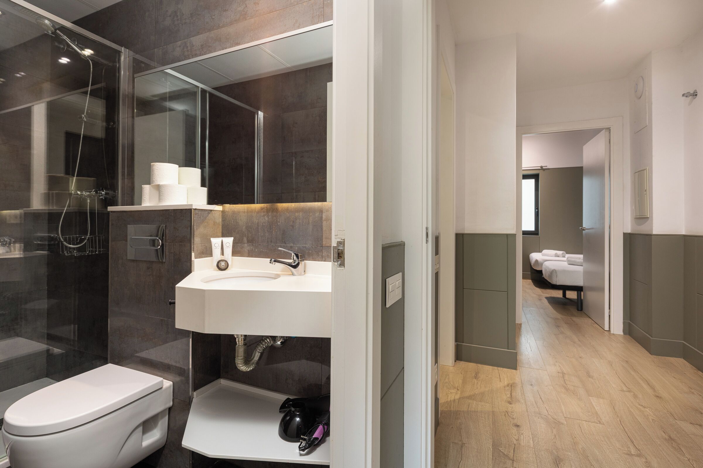 A modern bathroom with a glass-enclosed shower, a white sink, and a toilet.